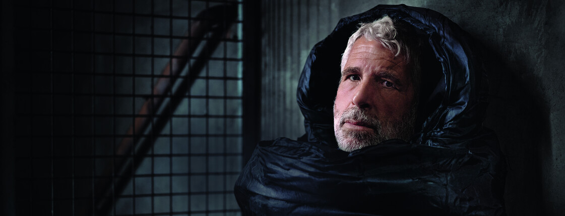 Der Fernsehmoderator Dirk Stermann als Obdachloser im Schlafsack abgebildet