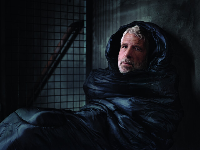 Der Fernsehmoderator Dirk Stermann als Obdachloser im Schlafsack abgebildet