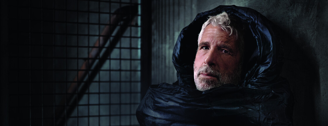 Der Fernsehmoderator Dirk Stermann als Obdachloser im Schlafsack abgebildet