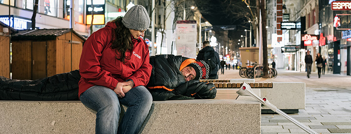 Mitarbeiterin spricht mit Obdachlosem
